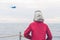 A boy in a red jacket looks at the sea waves in stormy rainy weather. Landing plane above sea waves in stormy rainy weather