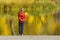 Boy in red jacket standing on the pier with leaves in his hand.