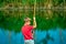 A boy in a red shirt throws a fishing rod on the catch river