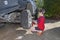 Boy in red t-shirt unscrews the nuts on the wheel of large off-road car. Child unscrews  nuts with cross wrench in the yard house