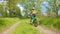 A boy rides a bicycle on a path in the forest. The road in the spring park.