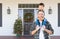 Boy Riding Piggyback on Shoulders of Father On Christmas Decorated Front Porch