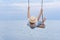Boy riding on rope swing over the water and lifted high legs. Holidays at sea with children