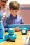Boy at the robotics lesson. Teacher shows brand new Wonder workshop clever robot Dash. STEM