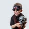 A boy rocker in black glasses, scarf, bandana and with a skull in his hands on a light background