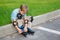 Boy with rollerblades sitting on edge of road.