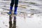 Boy in rubber blue rainboots jumping to dirty puddle