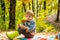 Boy in rubber boots relaxing in forest. Cute tourist concept. He likes hiking. Kid sit on plaid forest picnic. Child