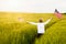 Boy runing with the american flag on the green wheat field celebrating national independence day. 4th of July concept