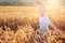 Boy running and smiling in wheat field in summer sunset