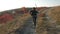 A boy runs down the hill with a wooden sword against the backdrop of a mountainous landscape