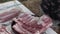 A boy`s hand pouring salt over a raw pork rib to cook on the grill.