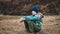 A boy with a sad look is sitting on the dry grass on the Bank of the river. Cool shots. Feelings and emotions