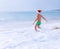 Boy in Santa hat runs to swim in ocean waves. Christams holiday