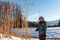 Boy with Santa red hat against a winter landscape background. Happy smiling child in the snow at Christmas standing beside tall