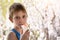 Boy of school age in breathing mask inhaler on a background of flowering trees. Home treatment. Prevention