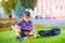 Boy, schoolkid reading book in colorful park