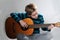 Boy schools himself to play the  acoustic guitar