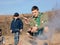 Boy Scout Cooking Sausages on Stick over Campfire