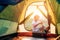 Boy sets up touristic tent ob sunset forest glade