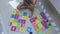 Boy in shorts with bare feet is playing with puzzle mat, alphabet puzzles on floor on balcony .