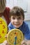 Boy Showing Yellow Clock With Teacher In Background