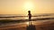 Boy silhouette on the beach at sunset runs into the sea