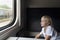 Boy sits in a compartment carriage and looks out the window. Travel by railway