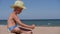 Boy sits on the Golden sand. The child wears a straw hat with a large brim. Child playing in the sand on the beach