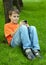 Boy sits on grass plays with electronic game