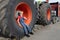 boy sits in a huge tractor wheel, looks into the frame, shows like with his hand, smiles