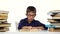 Boy sits at the table leafing through the pages of a book. White background.