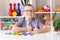 The boy sits at the table and makes words out of letters