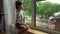 A boy sits at a wet window during the rain and looks at the street