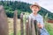 Boy sits on wooden fence on country side