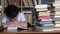 The boy sits at a wooden table and reads a thick book.