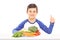 Boy sitting behind a plate full of fresh vegetables