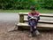 Boy Sitting on a Bench Reading with a Squirrel Nearby