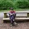 Boy Sitting on a Bench Reading with a Squirrel Nearby