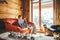 Boy sitting on cozy couch at living room and his beagle dog watching in wide window in cozy home atmosphere. Peaceful moments of