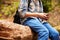 Boy sitting in a forest using a smartphone, close up