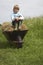 Boy Sitting On Hay In Wheelbarrow At Field