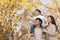 Boy sitting on his fathers shoulders in a park with family in Autumn