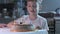 Boy sitting at kitchen table and blowing candles on birthday cake, making wish