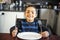 Boy sitting at the kitchen table with empty plate