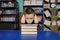Boy sitting in library, putting head on pile of book