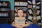 Boy sitting in library, putting head on pile of book