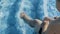 Boy sitting on pool edge and kicking with their legs splashing the water