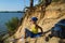 Boy sitting on sand cliff looking to sea. Travel and tourism concept