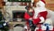 Boy sitting on santa`s lap, child giving saint nicolas his cristmas wishlist in envelope, holiday